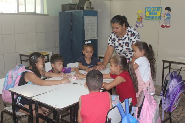 Kinderen maken samen met een juf hun huiswerk aan tafel